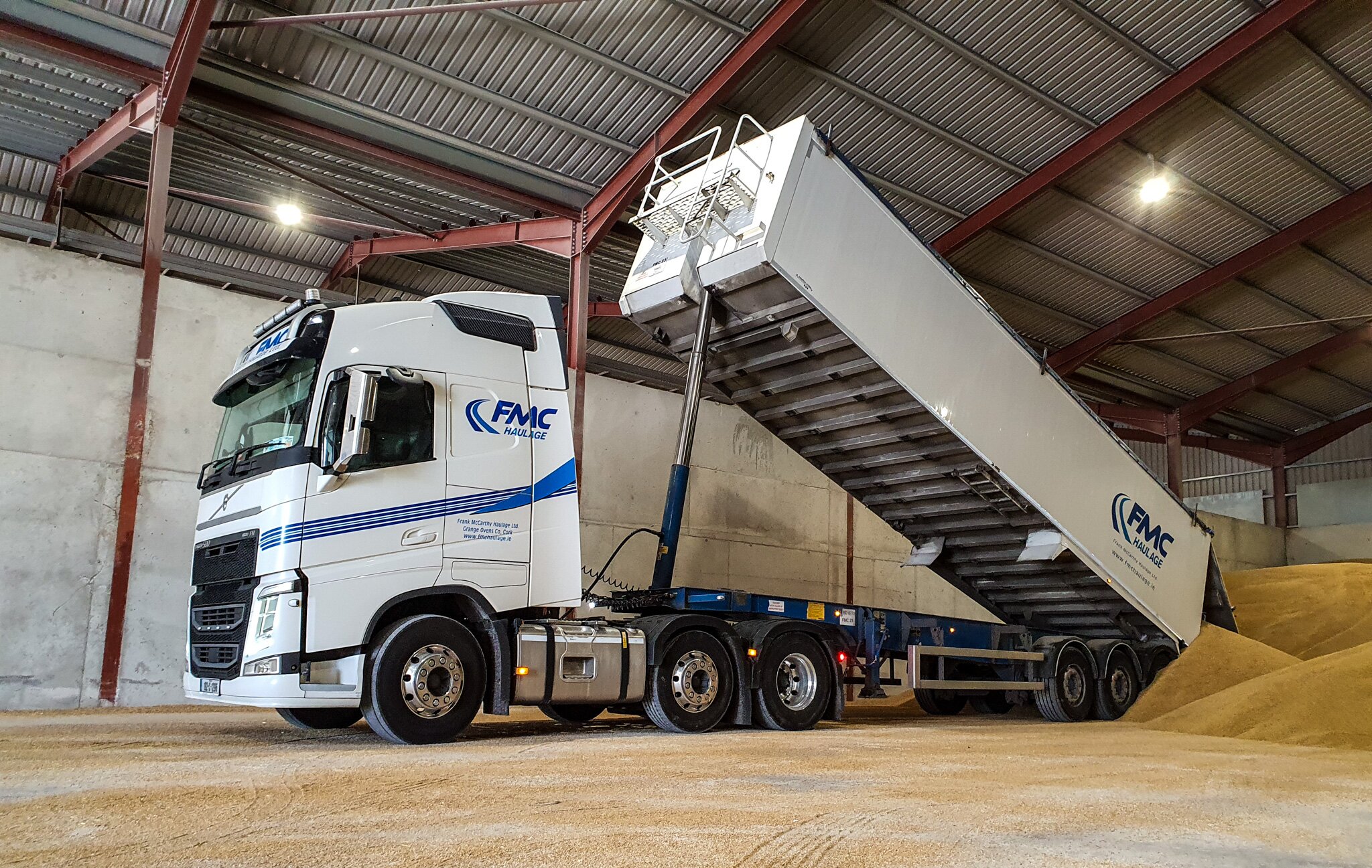 FMC Haulage Volvo tipper trailer discharging grain inside a controlled storage shed